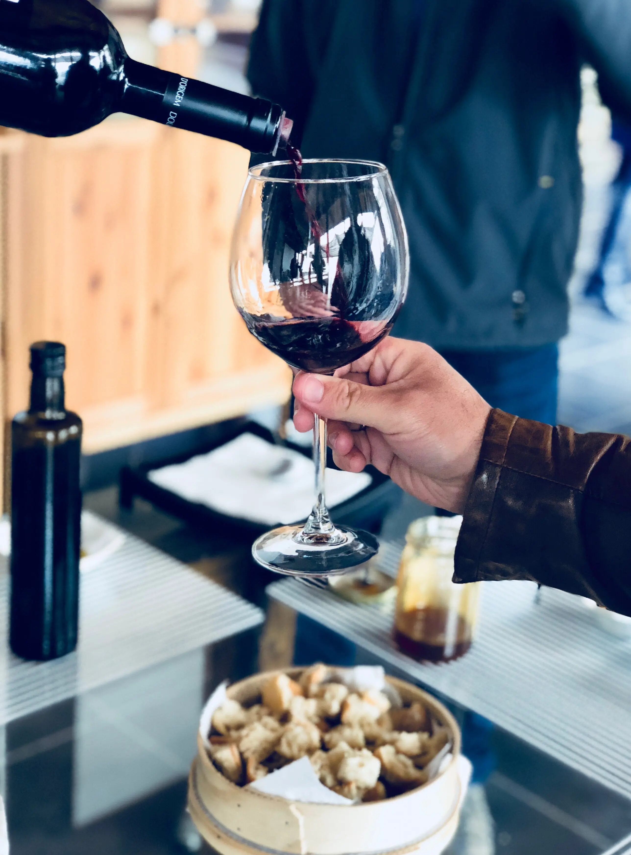 Nahaufnahme einer Hand, die Wein in ein Glas einschenkt.