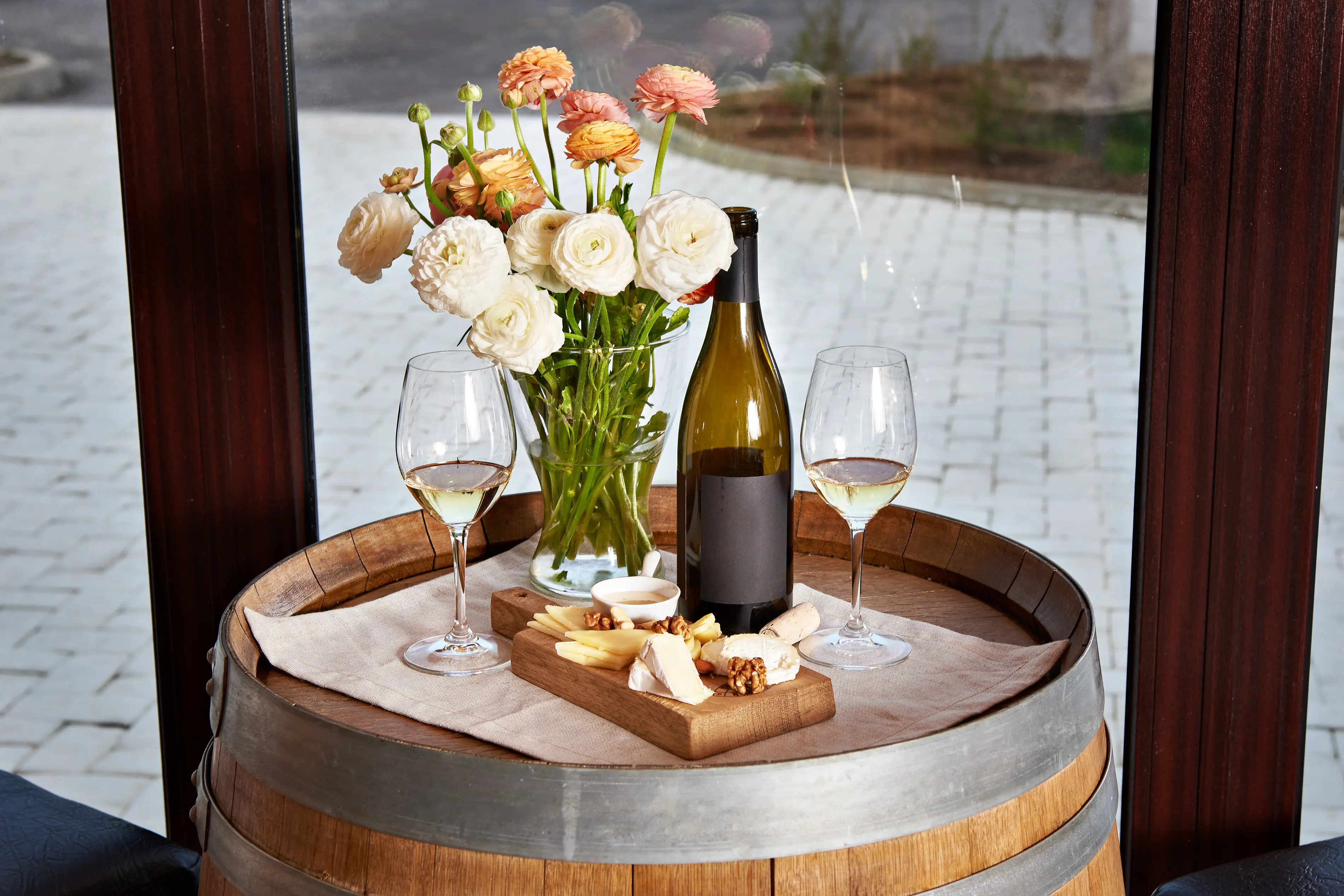 Flasche, Weingläser mit Weißwein und Käsevorspeise auf einem Fass.